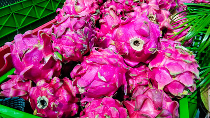 A pile of exotic fruit called dragon fruit, in a green basket