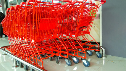 Red shopping trolleys are neatly lined up in the corner of a supermarket.