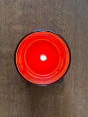 A red candle is lit in a glass jar