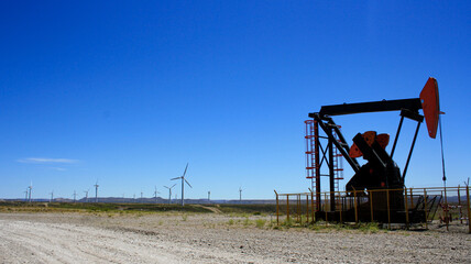 Oil field with wind farm in out of focus background.