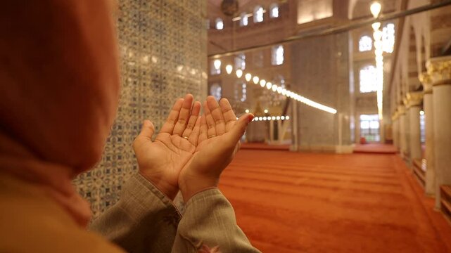Muslim young woman in hijab is praying in mosque.