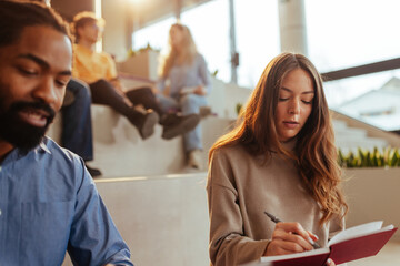 University students taking notes and listening to a lecture in modern university hall