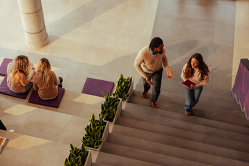 University students and teacher discussing on stairs in modern building