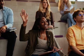 University student raising hand in lecture hall asking question