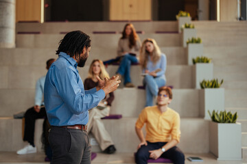 University professor gesturing while giving a lecture to diverse students in modern auditorium