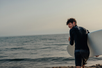 Male surfer walking into the sea carrying a surfboard