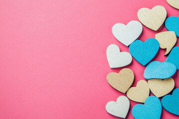 Obraz premium Colorful wooden hearts arranged on a pink background for Valentine's Day celebration