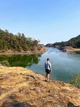 A man admiring a beautiful view of a cove on a beautiful summer day surrounded by forest and ocean on Jedediah Island Marine Park