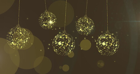 Fototapeta premium Image of gold christmas baubles swinging over stars and light spots on brown background