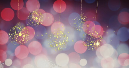 Image of gold christmas stars and baubles swinging over defocussed red and white lights