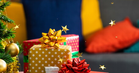 Naklejka premium Composite image of multiple golden stars floating against stack of christmas gifts