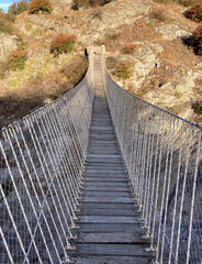 Close-up photo of an old wooden suspension bridge between mountain