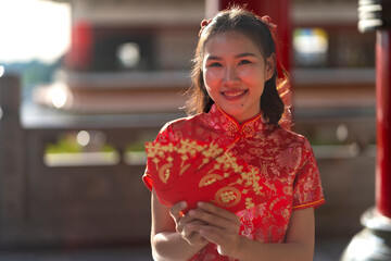 Smiling Woman in Red Qipao Holding a fan Red Envelope in Traditional temple