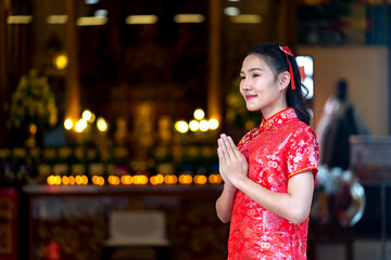Fototapeta premium Young Asian woman in Red Qipao Praying at Traditional Chinese Temple