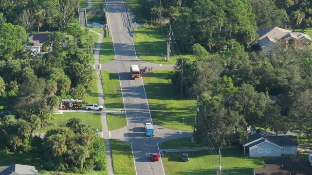 Yellow school bus picking up schoolkids on street bus stop for their lessons in Florida city suburbs. Public transport in the USA
