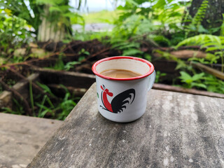 Cangkir kopi di atas meja kayu, latar belakang pemandangan toko tradisional yang alami dan buram....