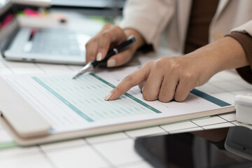 A woman is pointing at a graph on a piece of paper. The graph shows a comparison between two sets of data. The woman is using a pen to highlight the differences between the two sets of data