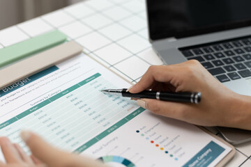 A woman is pointing at a graph on a piece of paper. The graph shows a comparison between two sets of data. The woman is using a pen to highlight the differences between the two sets of data