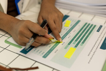 A woman is writing on a piece of paper with a pen. She is writing on a piece of paper that says 