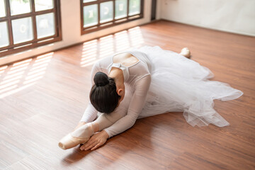 Asian girl ballet dancer gymnastic exercises in studio for body flexibility Ballerina training stretches her leg and prepares for performance practice routine.