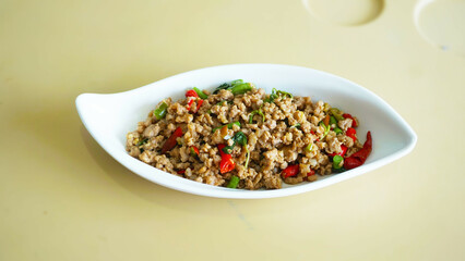 Authentic Thai Basil Pork, Pad kra pao Thai cuisine is a spicy and savory stir-fry dish featuring ground meat and holy basil in White Boat Shaped Dish.