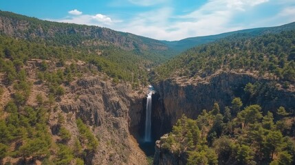 Majestic Waterfall Cascading Down a Rocky Cliff Surrounded by Green Forests