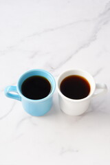 
淹れたてのコーヒーが入ったふたつのマグカップで、ふたりがコーヒーを飲みながら、打ち合わせをしているイメージ
