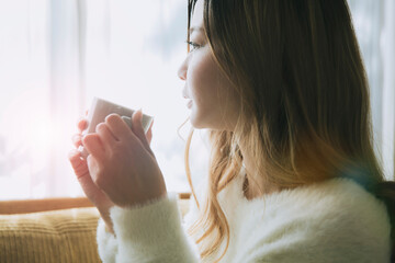 ソファでコーヒーを飲みながらリラックスする女性