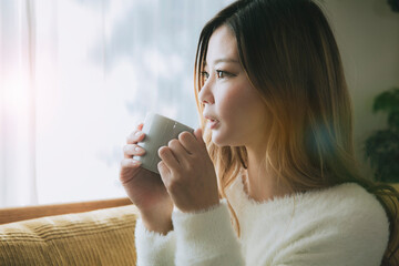 ソファでコーヒーを飲みながらリラックスする女性