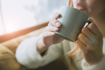 ソファでコーヒーを飲みながらリラックスする女性