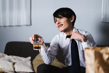 仕事終わりにテイクアウトの食べ物とお酒を飲む若いビジネスマン