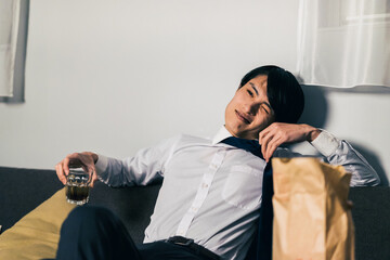 仕事終わりにテイクアウトの食べ物とお酒を飲む若いビジネスマン