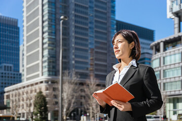 手帳を持って遠くを見つめる女性