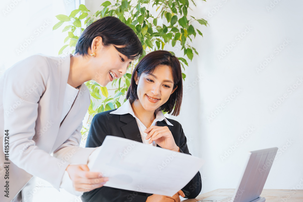 Poster 資料を見て相談する2人の女性（ビジネスイメージ）