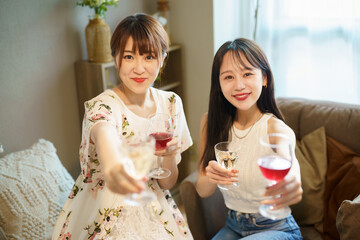 グラスを手に談笑する女性2人 © TAGSTOCK2