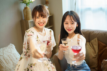 グラスを手に談笑する女性2人 © TAGSTOCK2