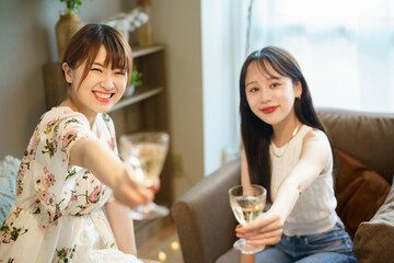 グラスを手に談笑する女性2人 © TAGSTOCK2