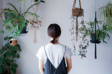 明るい植物のある室内でワンピース姿の後ろ姿の日本人女性