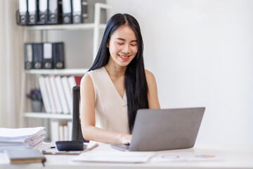 Businessasian woman using laptop computer in office. Happy young woman, entrepreneur, small business owner working online.
