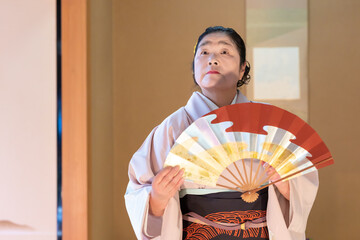 着物姿で扇子を持って日本舞踊を踊る年配の日本人女性