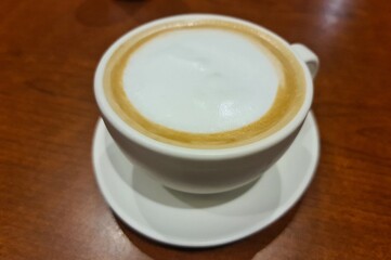 Cup of Hot latte coffee on the red oak color wooden table image
