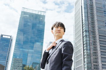 Fototapeta premium ビジネス街でクールに振り向く20代のスーツ姿のビジネスマンの男性