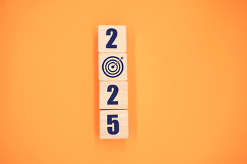 2025 letter with goal icon on wooden block on wooden table, orange background, happy new year 2025,...