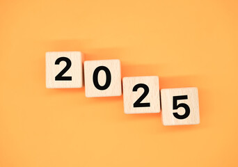 New year 2025 with 2025 wooden blocks on orange background. Start the new year 2025 with a goal...