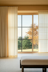 Natural light pours into a serene room with a view of autumn trees and a peaceful landscape