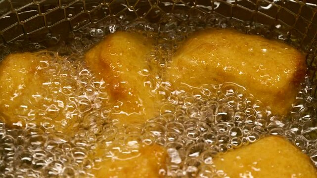 Closeup slow motion crispy fried chicken meat nuggets deep frying in boiling oil