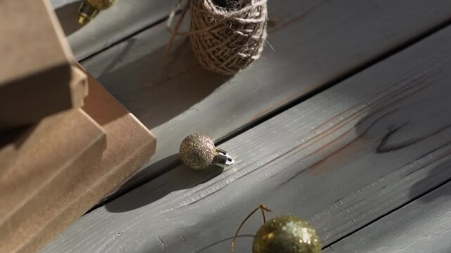Holiday decor. Packing holiday gifts. Gift boxes, natural twine and Christmas gold balls on a wooden background.