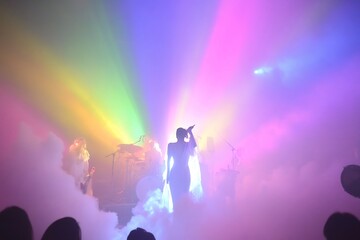 Fototapeta premium Vibrant Silhouette of Performer on Colorful Lit Stage with Beams of Light