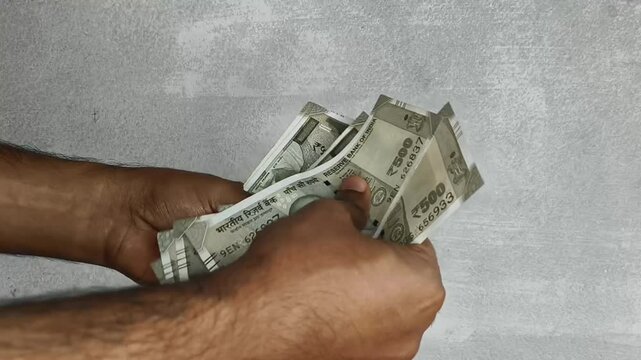 Hand counting bunch of indian currency, money or bank notes bundle of five hundred rupee. Close up macro top view. Financial, savings, economy, business, salary and investment concept background.