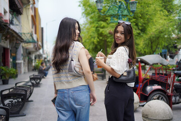 back view of two asian women and look back to the camera while walking on street